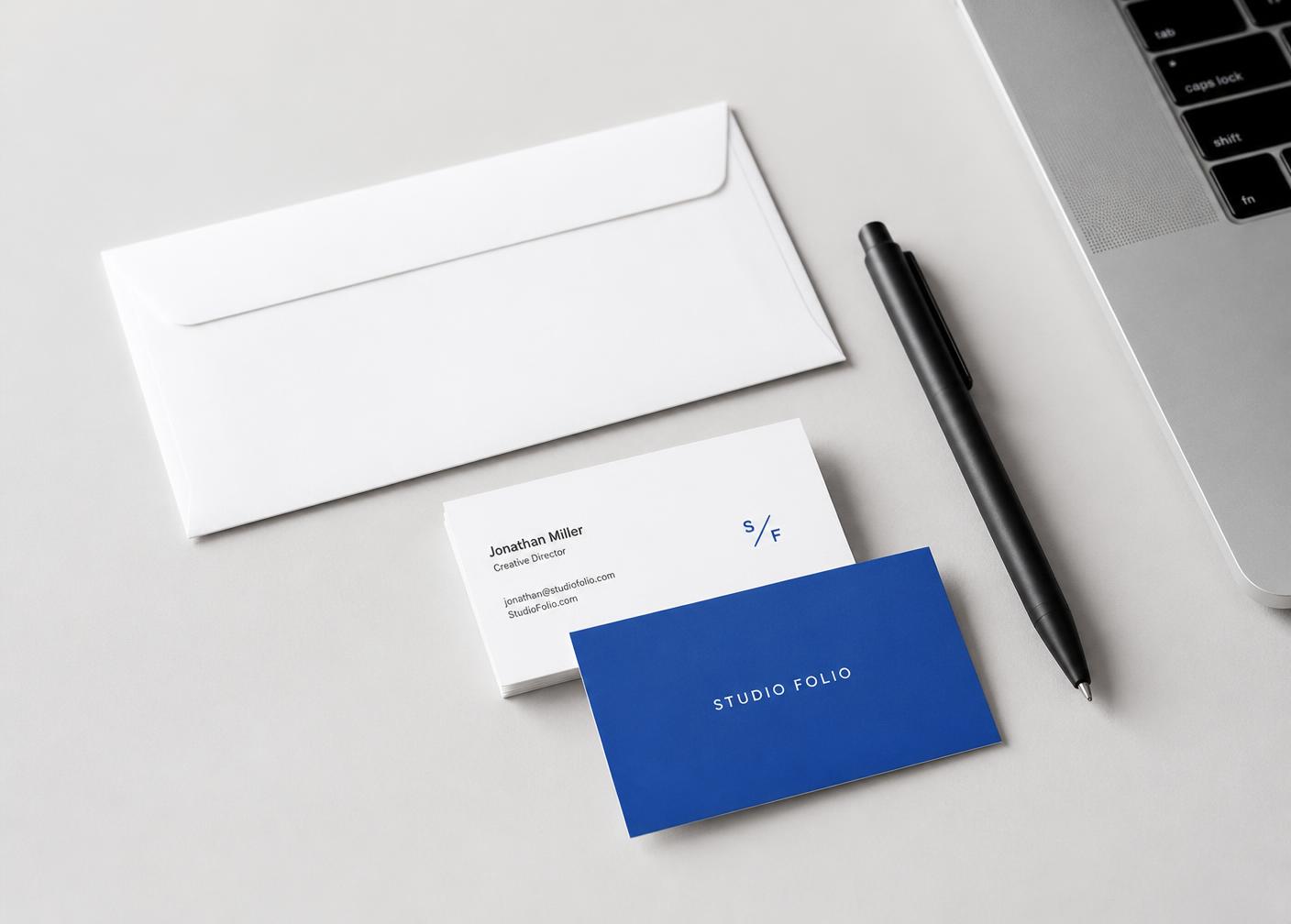 Business cards, envelope and pen on a light gray desk