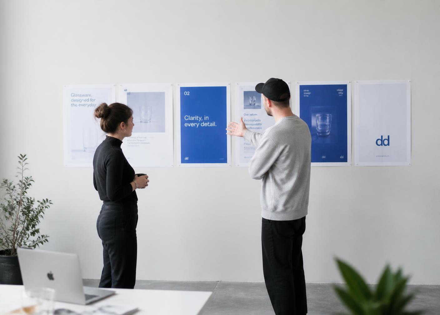 Two designers reviewing printed brand posters in a bright studio